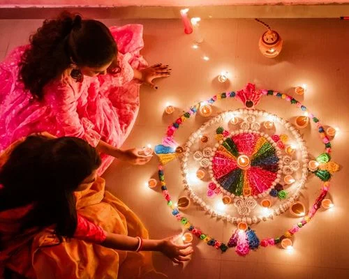 Diwali decorations with lighted diyas and flowers Two Indian Wowen Lighting Diyas and decorating Rangoli with flowers on the occasion of Diwali Festival, The Festival of Lights