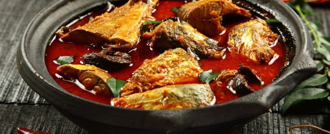 Goan fish curry in a clay pot garnished with Curry leaves