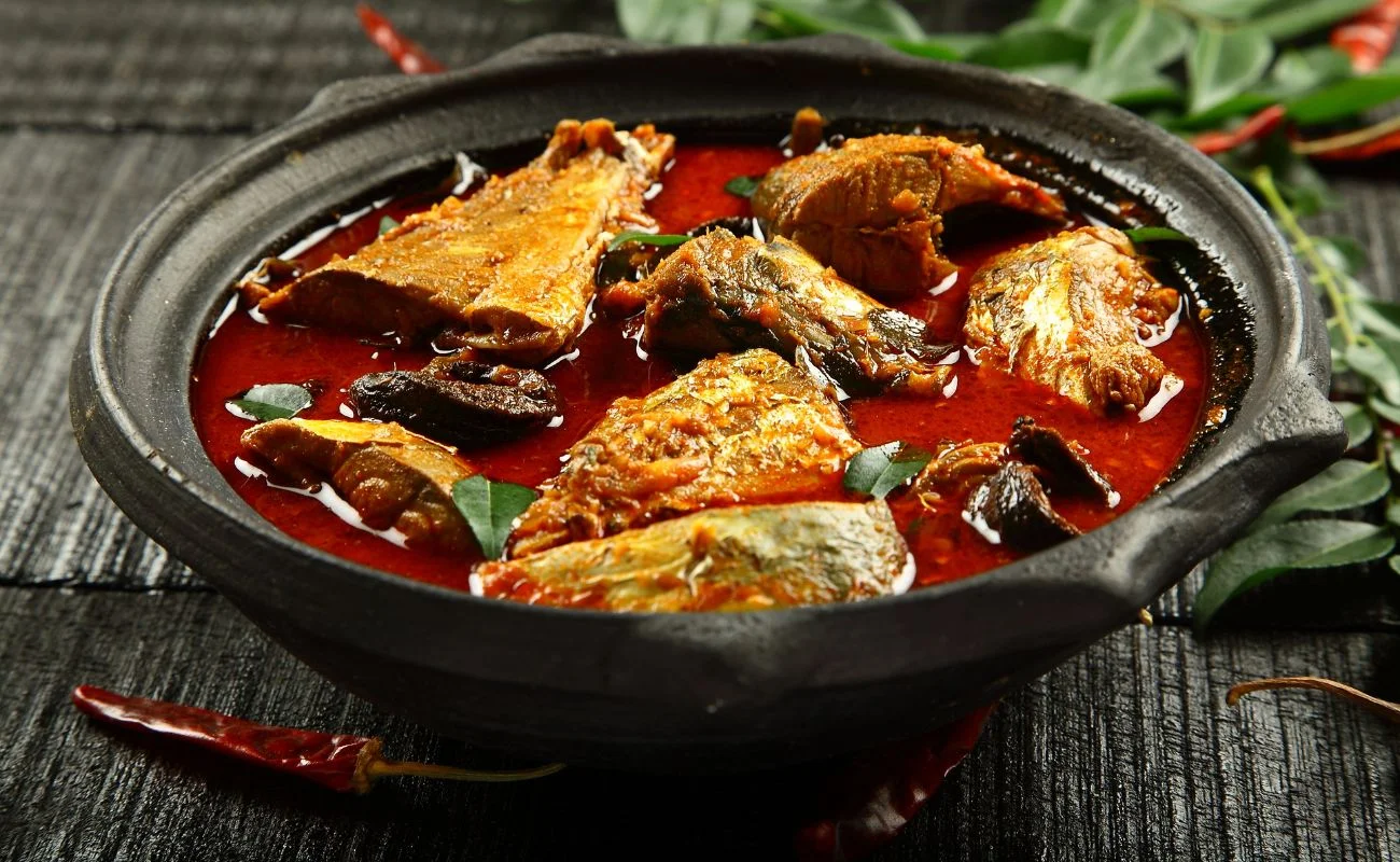 Goan fish curry in a clay pot garnished with Curry leaves