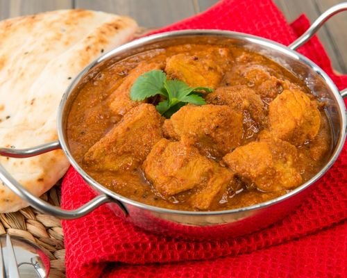 Goan Pork Vindaloo dish with a spicy red sauce, garnished with fresh cilantro.