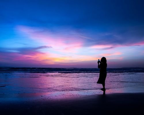 Girl standing on shore at evening in Goa beach sunset