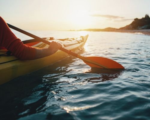 Close-up of kayak paddle on calm waters, ready for an exhilarating kayaking adventure.