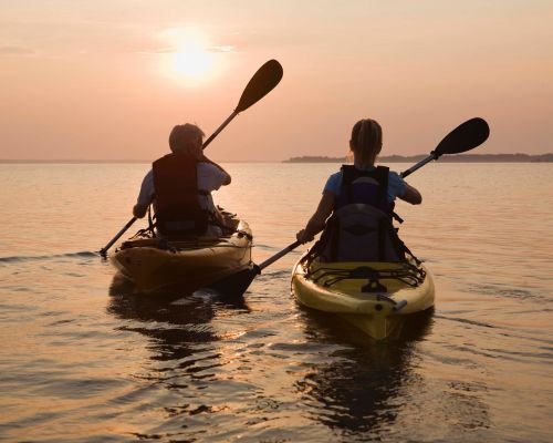 Two kayakers enjoying a serene sunset kayaking experience