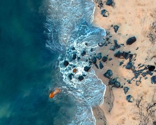 Aerial view of Patnem beach with turquoise blue water and sandy shore, surrounded by lush green trees.