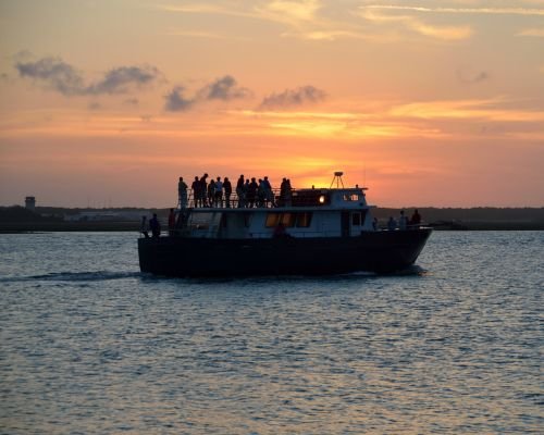 Small cruise ship with passengers enjoying sunset on the river